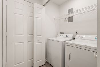 a white washer and dryer in a white laundry room with white doors at Latitudes Apartments, Indianapolis, Indiana